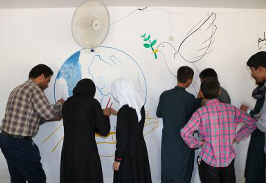 Members of peace and reconciliation drawing pictures on wall depicting peace