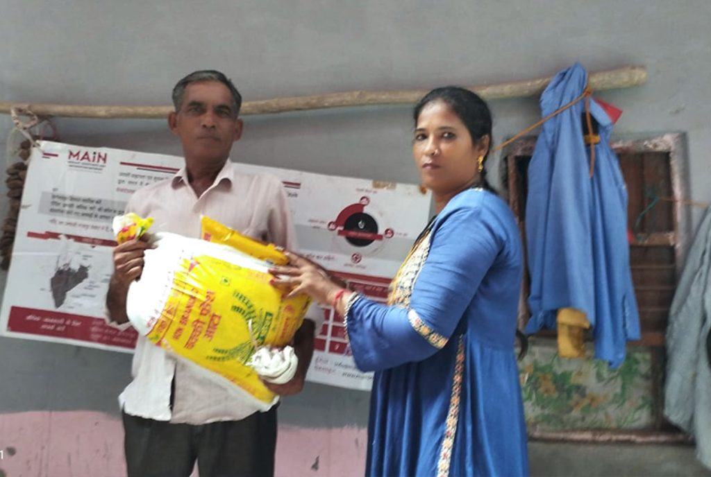 Migrant Assistance worker handing over essential items to people affected by recent Delhi floods.